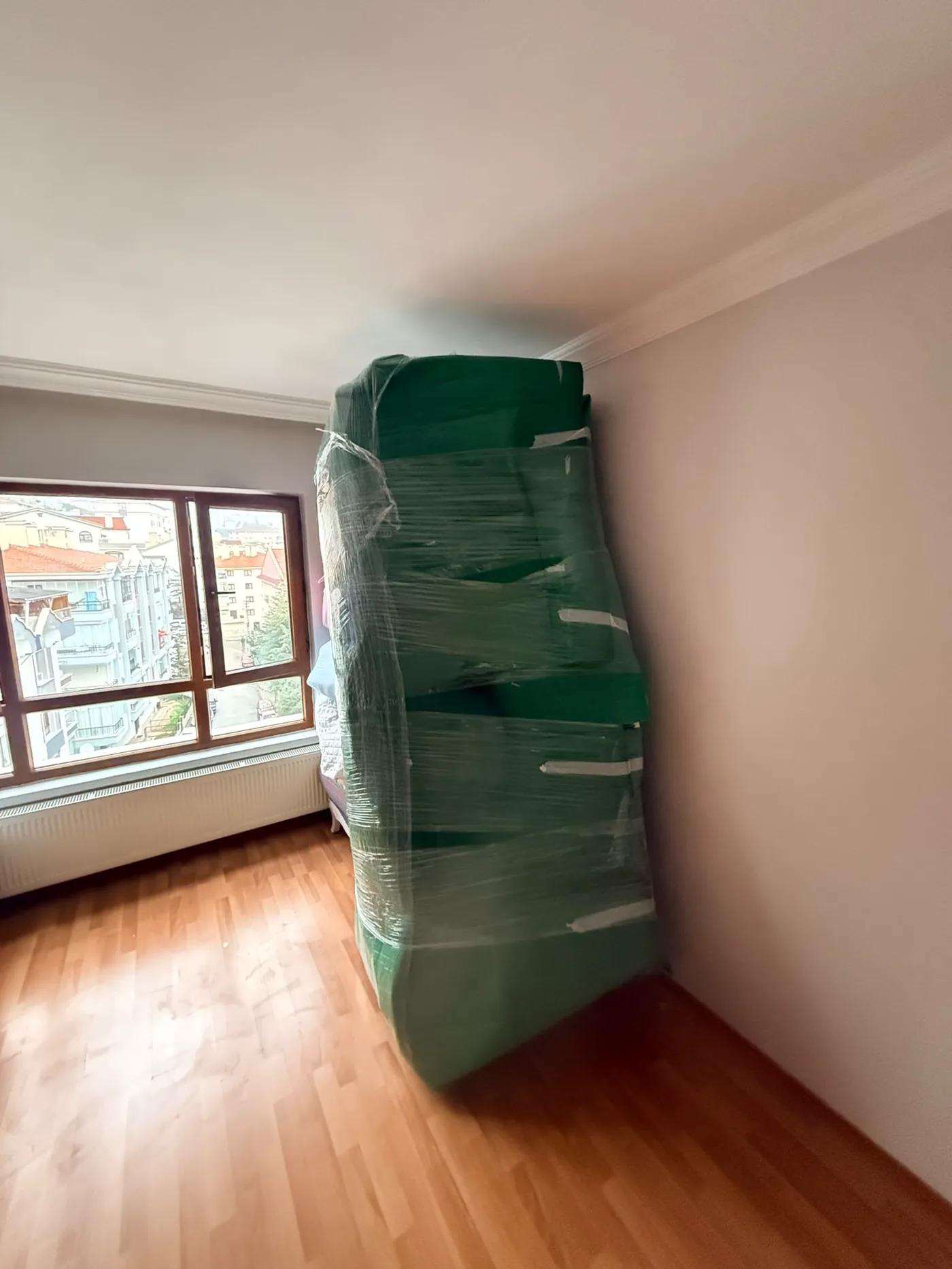 Nakliyat sırasında çizilmeyi önlemek için yeşil battaniyeyle paketlenen mobilya